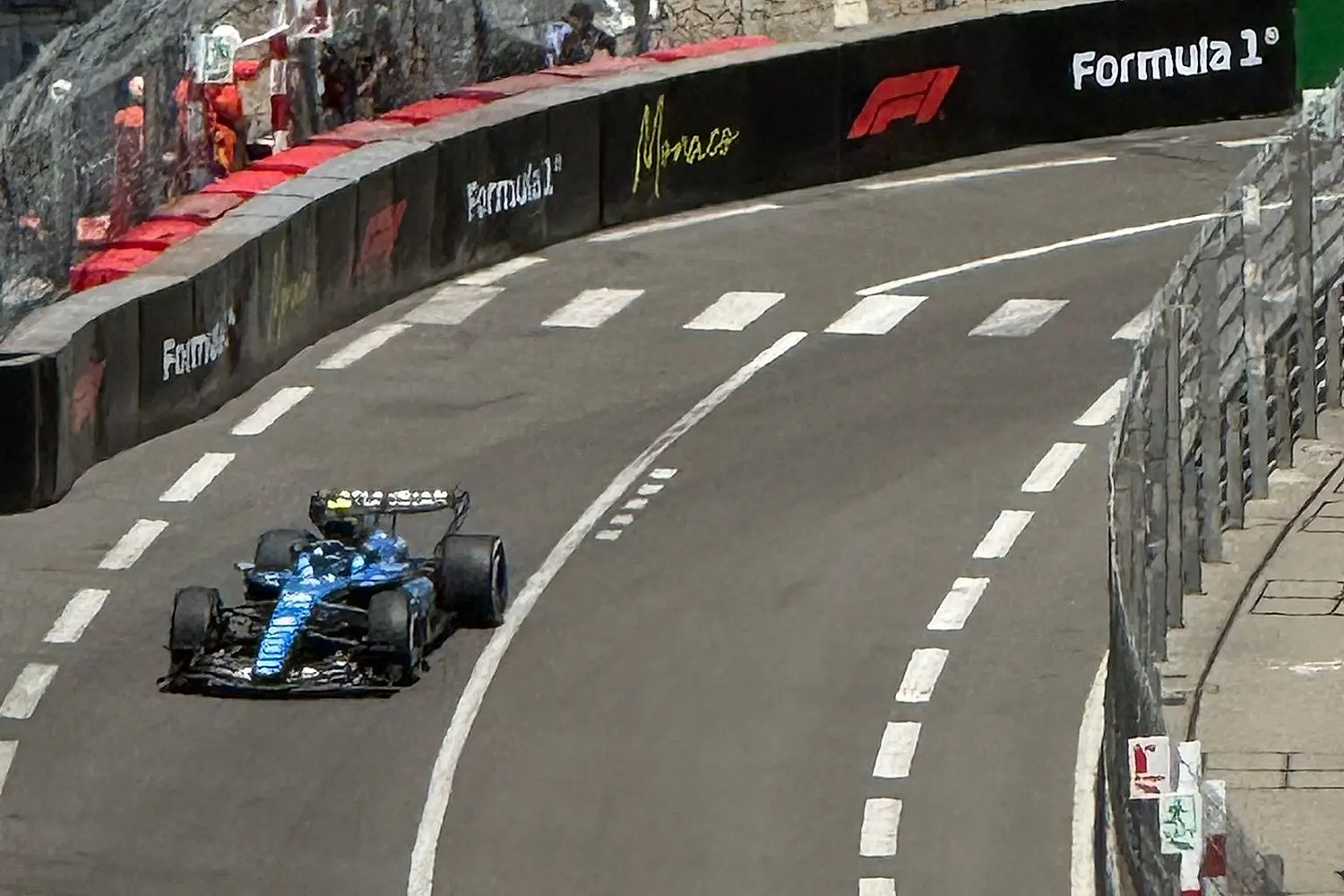 A racing car taking a corner of the street circuit during the Grand Prix, seen from above.