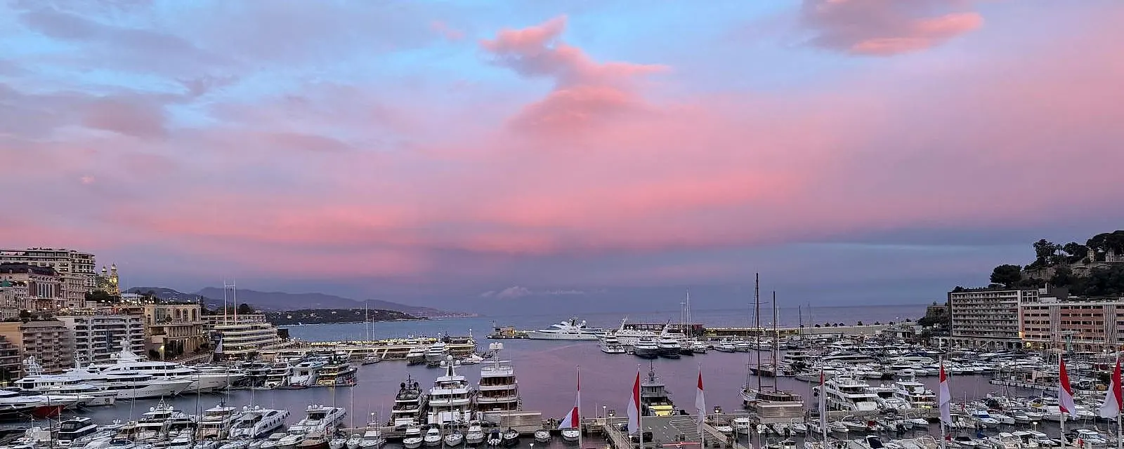 The harbour at dusk under pink clouds, the coast stretching away beyond it.