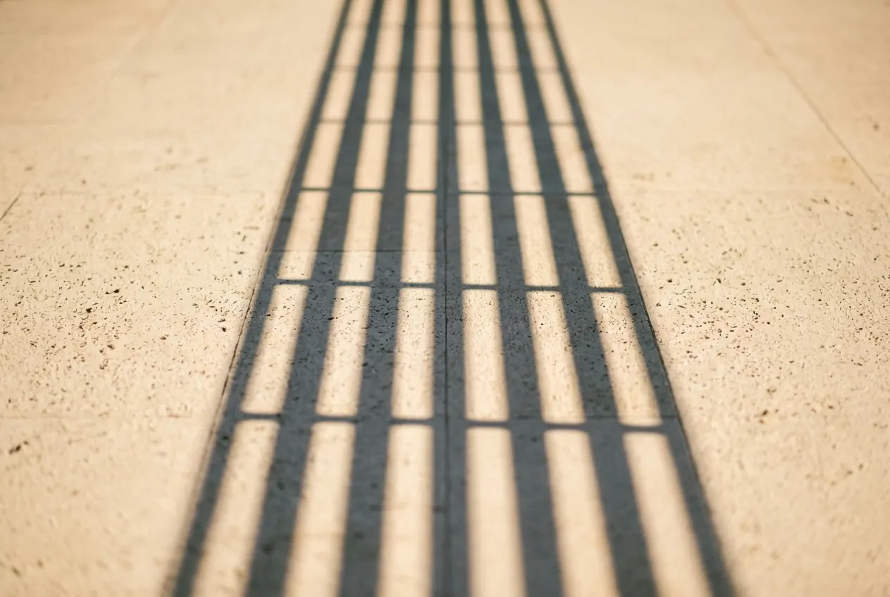 The shadow of a balustrade falling in stripes across pale stone in late sun.